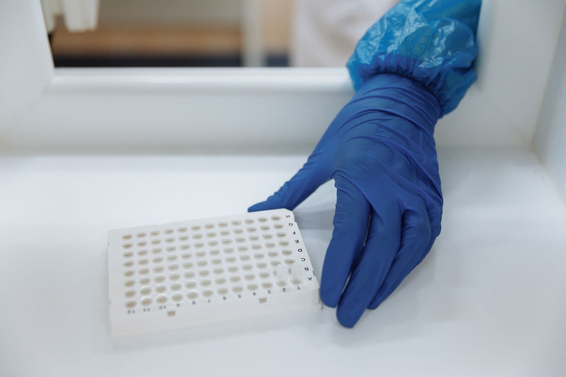 A gloved technician handling sample vials in a laboratory