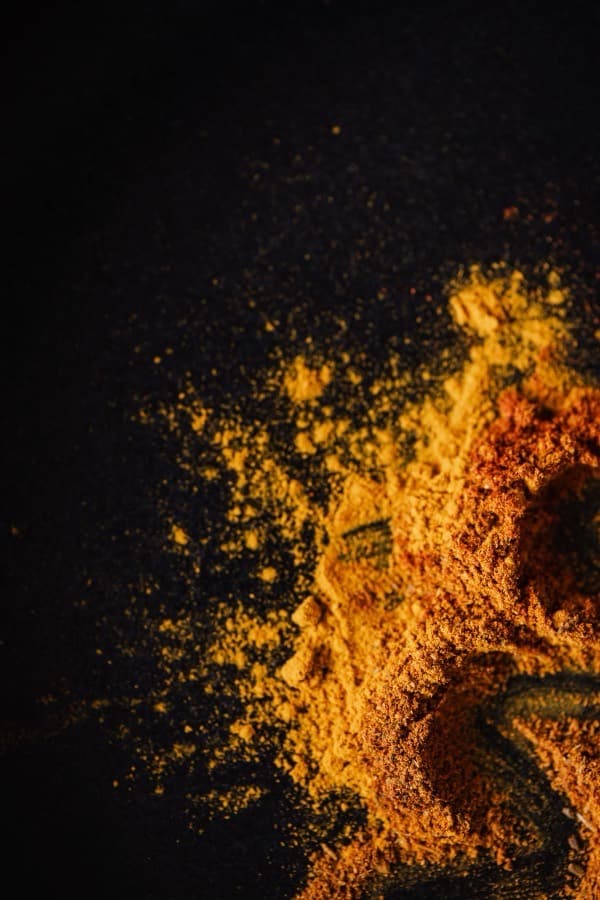 Milled spice powder in warm gold and amber on a dark surface