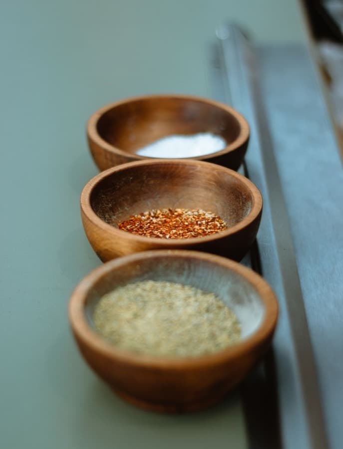 Wooden bowls of salt, chilli flakes and dried seasoning
